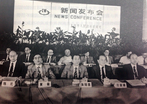 1990年9月10日，朱�F基出席上海市政府举行的新闻发布会。前排右一为财政部副部长项怀诚，右二为市政府顾问汪道涵，左一为中国人民银行副行长陈元，左二为市委副书记、副市长黄菊；后排左三为是对外经济贸易委员会副主任兼外国投资工作委员会主任沈被章。