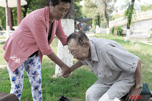 小女兒攙扶著老人坐在公園的石凳上乘涼。