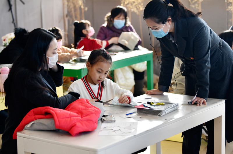 2021年1月1日，小朋友在老師和家長的注視下裁剪布料用來制作漢服手工藝品。新華社記者 李然 攝