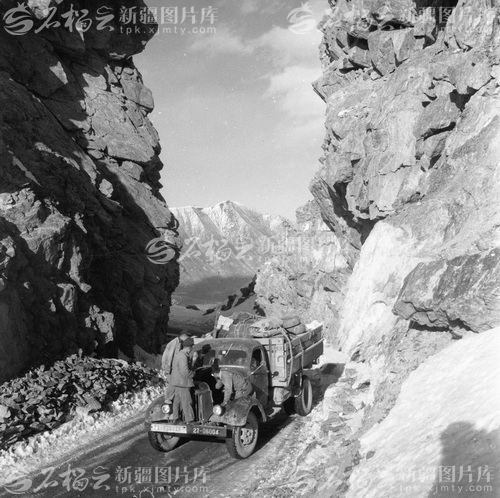 驾驶员在翻越乌库公路天格尔冰峰胜利达坂山顶垭口（老虎口）时维修车辆。（范博摄 新疆图片库供图）