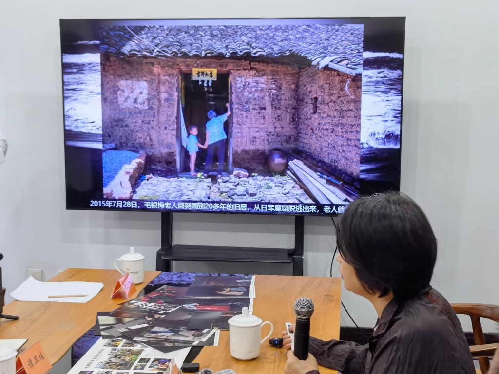 8月14日，晏美华介绍自己拍摄的韩裔日军“慰安妇”制度受害幸存者毛银梅的照片。新华社记者 邱冰清 摄