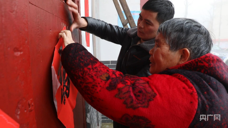 彭德良与70多岁母亲贴春联(央广网记者 郇康新 摄)