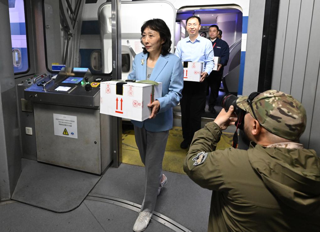 護送文物歸國的工作人員手捧裝載著子彈庫帛書的保護箱走出客機（2025年5月18日攝）。新華社記者 李賀 攝