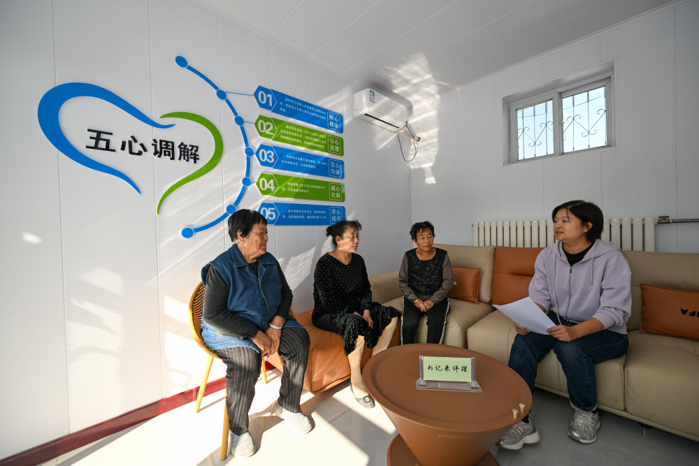 在天津市宁河区芦台街道金华路社区,社区党总支副书记吴蕊(右一)就社区监控设备安装问题为社区居民进行解答(2024年10月11日摄)。金华路社区积极践行新时代“枫桥经验”,将原社区居委会闲置用地提升改造成为联络群众的基层综合治理阵地——“解铃小院”。新华社记者 孙凡越 摄
